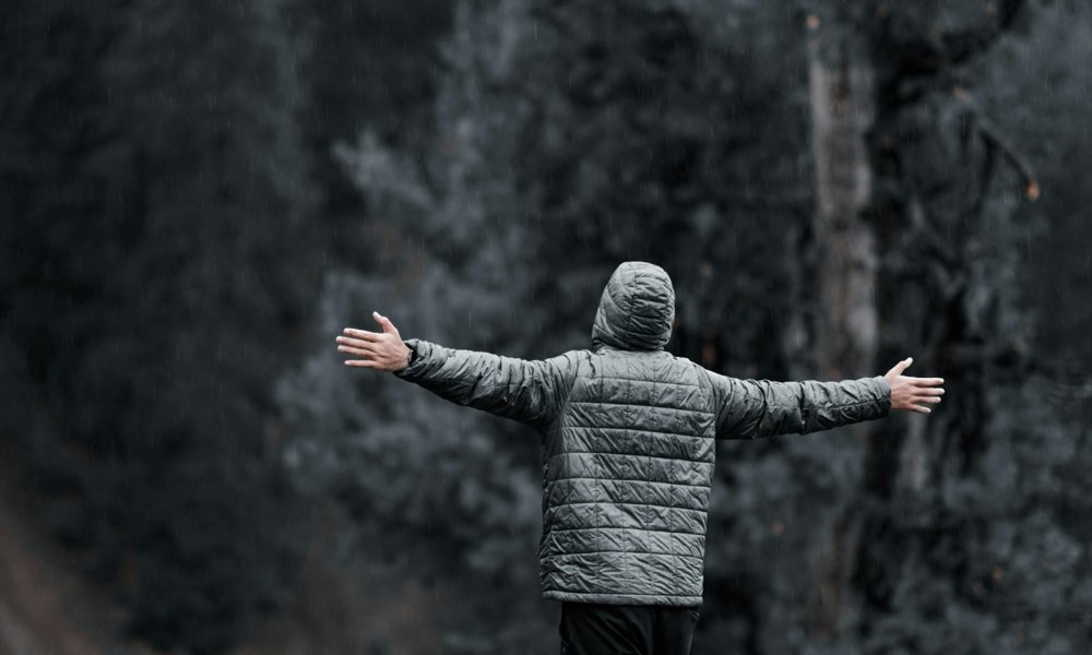 Person spreading arms on a mountain cliff