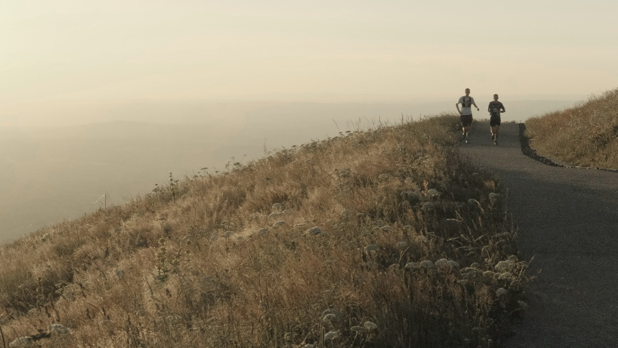 Runners on a hill path at sunset